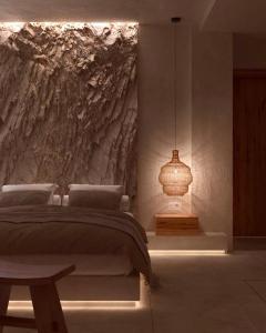 una camera con un letto e un muro in pietra di Elaia Luxury House a Archangelos