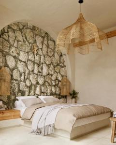 a bedroom with a stone wall and a bed at Elaia Luxury House in Archangelos