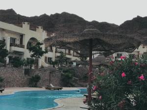a pool with an umbrella next to a building at Poolfront Sea View Chalet Top Rated In Dahab in Dahab