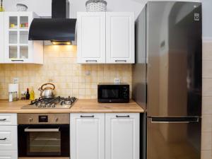 kuchnia z białymi szafkami i lodówką ze stali nierdzewnej w obiekcie Apartament Greta w Złotym Stoku