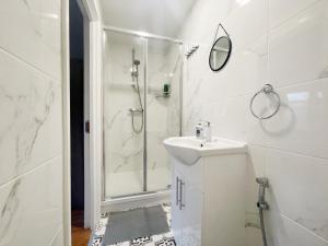 bagno bianco con doccia e lavandino di Large Cosy Property 15min from Central London a Londra