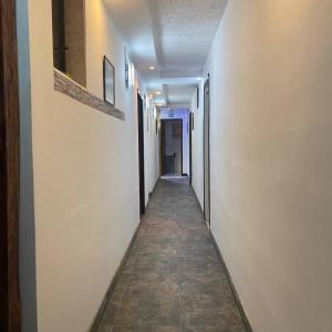 an empty hallway with a long corridor with white walls at Calu L' Petit Hostel in Quito