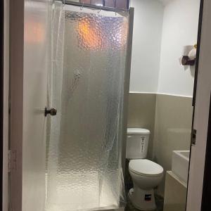 a bathroom with a toilet and a glass shower at Calu L' Petit Hostel in Quito