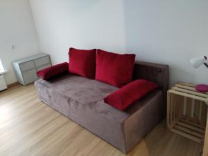 um sofá com almofadas vermelhas numa sala de estar em Apartament Tereska em Duszniki Zdrój