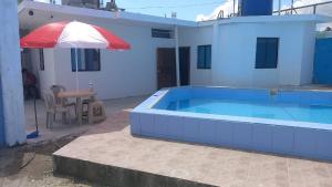 a swimming pool with an umbrella next to a house at Casa Tonsupa in Tonsupa