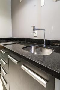 a kitchen sink with a black counter top at Studio Oceanview in Rio de Janeiro