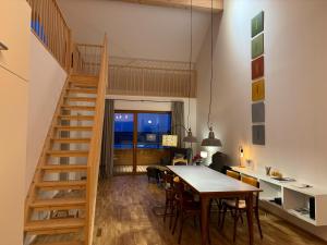 a kitchen and dining room with a wooden table and stairs at Gamsfels Balbina Galeriewohnung in Langen bei Bregenz