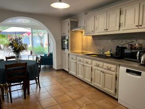 a kitchen with white cabinets and a table and a dining room at Domaine Le Clos des Oliviers in Sorbo-Ocagnano