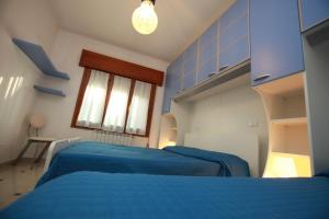 two beds in a room with blue walls and a window at Villa orchidea in Rosolina Mare