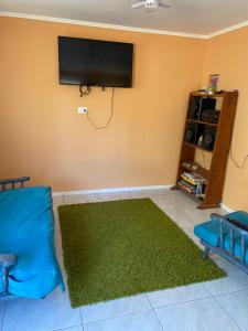 sala de estar con alfombra verde y TV de pantalla plana en Cabaña, en Chillán
