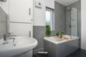 ein Badezimmer mit zwei Waschbecken, einer Badewanne und einem Spiegel in der Unterkunft NEW Poplar House - Stunning 4 Bedroom House in Stoke-on-Trent in Newcastle under Lyme