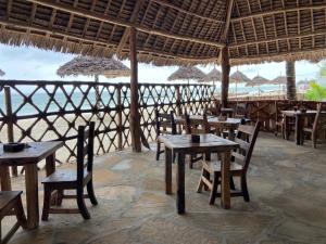 a restaurant with tables and chairs and a view of the ocean at Waka Waka in Pwani Mchangani
