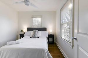 a white bedroom with a large bed and two windows at Amazing Location Spacious House in Atlanta