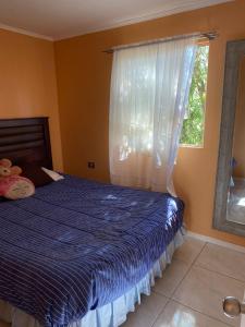 een slaapkamer met een bed met een blauw dekbed en een raam bij Cabaña in Chillán