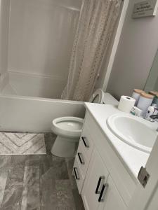 a white bathroom with a toilet and a sink at Stylish Basement Suite with Modern Comforts in Winnipeg