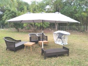 an umbrella with three chairs and a table under it at Suites Pineapple in Rock Sound