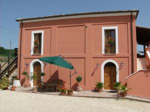 a pink house with a chair and an umbrella at Country House Agriturismo Ciuccunit in Bucchianico