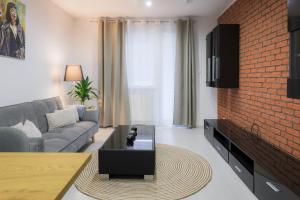 uma sala de estar com um sofá e uma parede de tijolos em Apartmán Štefánik #1 em Martin
