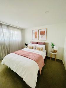 a bedroom with a large bed with white sheets and pink blankets at Queenstown Mountain Getaway in Queenstown