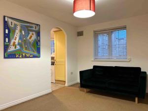 a living room with a black couch and a window at East London Apartment near Station & Free Parking in Romford