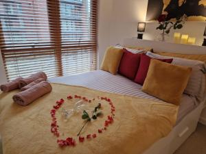 Luxury Modern Apartment Stay في شيفيلد: سرير عليه قلب مصنوع من الزهور
