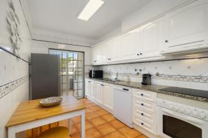 een keuken met witte kasten en een houten tafel bij Vilamoura - Cozy and Quiet Holiday Apartment in Vilamoura