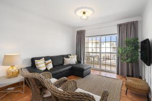 a living room with a black couch and wicker chairs at Vilamoura - Cozy and Quiet Holiday Apartment in Vilamoura