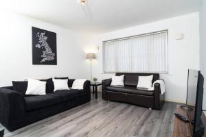 a living room with a black couch and a chair at Central Liverpool Gem 3 bedroom House Private Parking in Liverpool