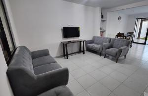 Una sala de estar con sofás y un televisor de pantalla plana. en Casa en Residencial San Andrés, en San Miguel