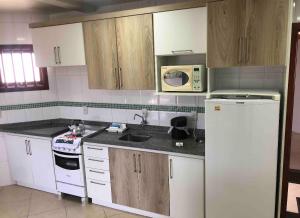 a kitchen with white cabinets and a white refrigerator at Pousada do centro Tramandaí Ap 3 in Tramandaí