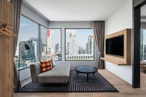 a living room with a couch and a large window at Moxy Bangkok Ratchaprasong in Bangkok