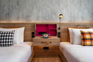 two beds in a hotel room with a tv at Moxy Bangkok Ratchaprasong in Bangkok