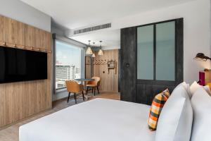 a bedroom with a large bed and a table with chairs at Moxy Bangkok Ratchaprasong in Bangkok
