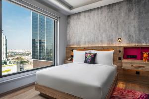 a bedroom with a bed and a large window at Moxy Bangkok Ratchaprasong in Bangkok +37 photos