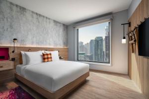 a bedroom with a white bed and a large window at Moxy Bangkok Ratchaprasong in Bangkok