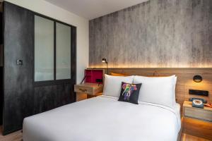 a bedroom with a white bed and a wall at Moxy Bangkok Ratchaprasong in Bangkok