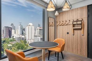 a dining room with a table and chairs and a large window at Moxy Bangkok Ratchaprasong in Bangkok