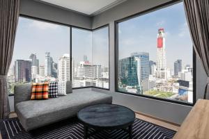 a living room with a couch and a large window at Moxy Bangkok Ratchaprasong in Bangkok