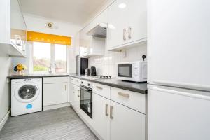 uma cozinha com armários brancos e uma máquina de lavar e secar roupa em Contemporary 5 Bedroom Flat em Killingbeck