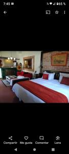 a hotel room with two beds with red and white sheets at Alonso Chacras Lodge in Chacras de Coria