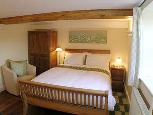 a bedroom with a large bed and a chair at Mouse Castle Barn in Hay-on-Wye