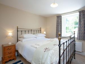 a bedroom with a large bed and a window at South Wing Cottage in Rumleigh