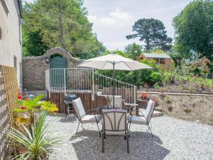 a patio with a table with an umbrella and chairs at South Wing Cottage in Rumleigh