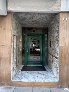 una puerta verde a un edificio con una persona caminando a través de él en Caballito Apartamen Premiun en Buenos Aires