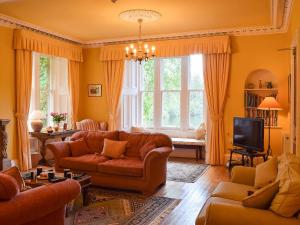 a living room with a couch and a tv at Creag-ard House in Aberfoyle
