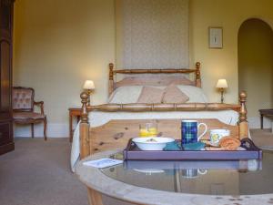 a bed with a glass table with a tray of food at Creag-ard House in Aberfoyle