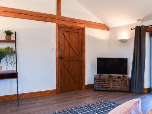 a living room with a tv and a wooden door at Millside Cottage in Natland