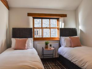two beds in a small room with a window at Millside Cottage in Natland
