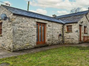 a stone house with a wooden door and a yard at Millside Cottage in Natland