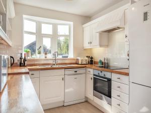 una cucina con armadi bianchi e lavandino di Sea Star a Winterton-on-Sea